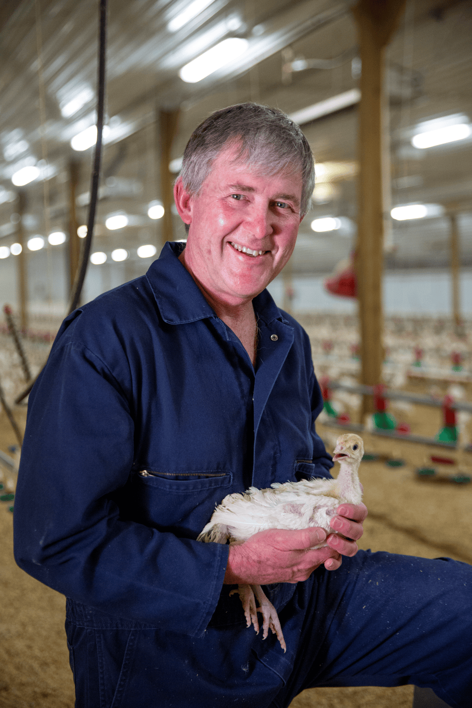 This is a photo of a man holding a chicken, while smiling.
