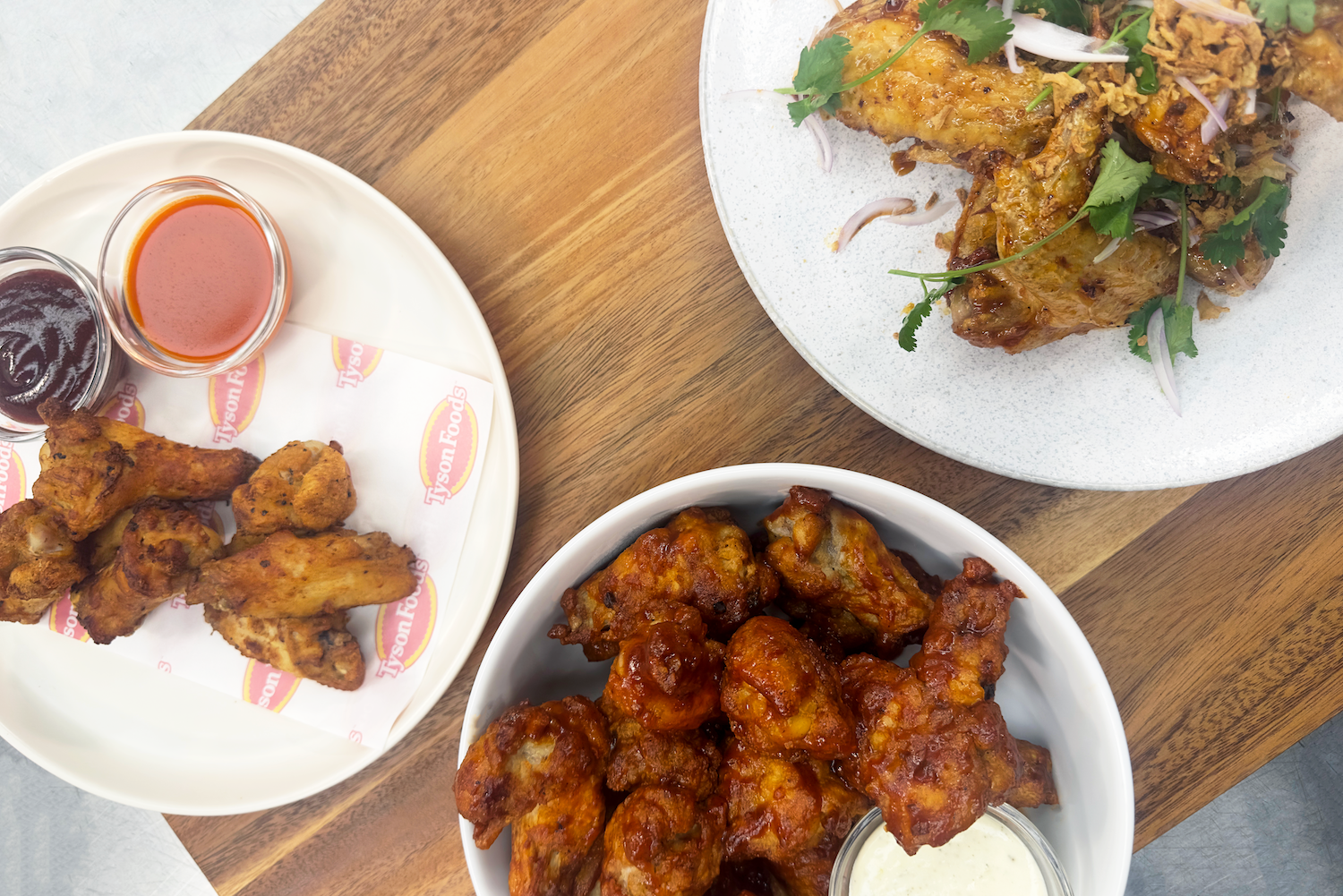 Three plates of chicken wings with various sauces