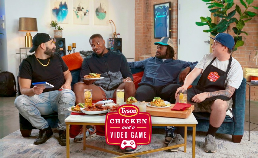 This is a photo of men sitting around a coffee table with chicken being served.