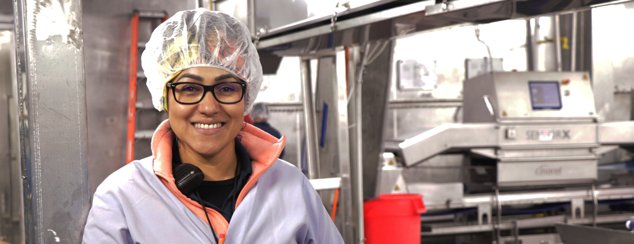 Team member in hairnet smiling with glasses