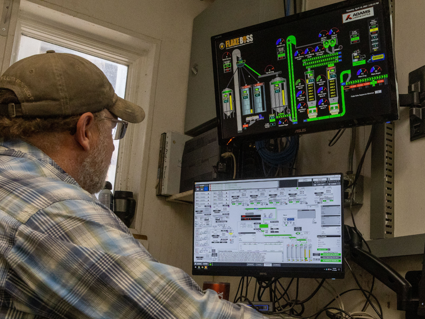 This is a photo of a farmer monitoring grain processing and output.
