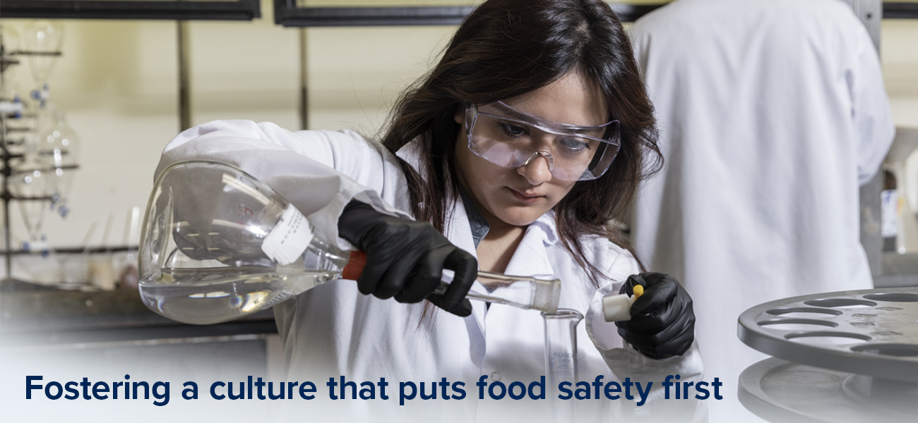 Woman in lab pouring liquid into a beaker
